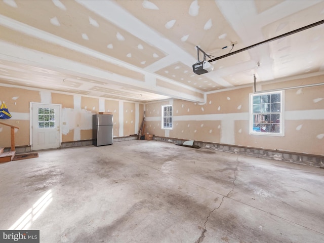 garage featuring a garage door opener and stainless steel refrigerator