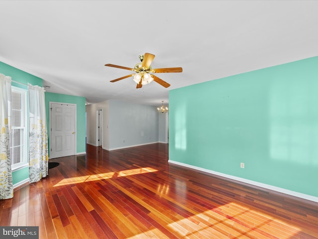 empty room with ceiling fan with notable chandelier and wood-type flooring