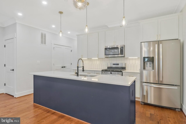 kitchen with a kitchen island with sink, sink, stainless steel appliances, and white cabinets