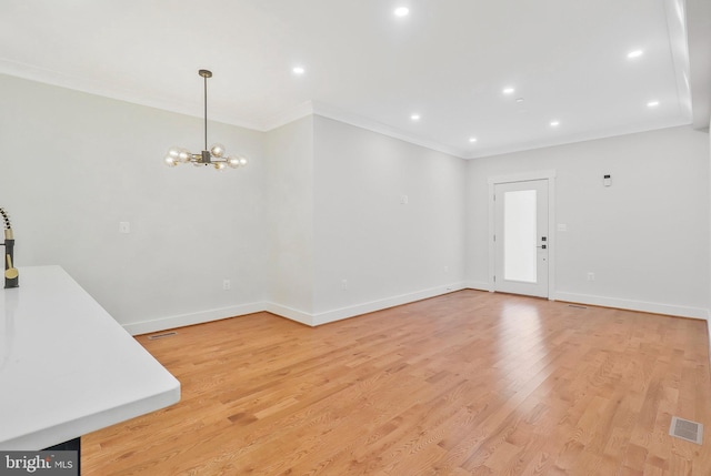 unfurnished living room with crown molding, a chandelier, and light wood-type flooring