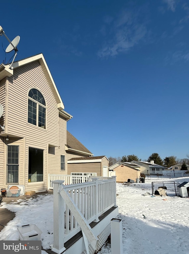 view of snow covered exterior featuring a wooden deck and a storage unit