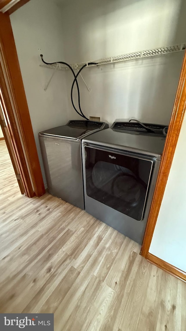 laundry area with separate washer and dryer and light hardwood / wood-style flooring