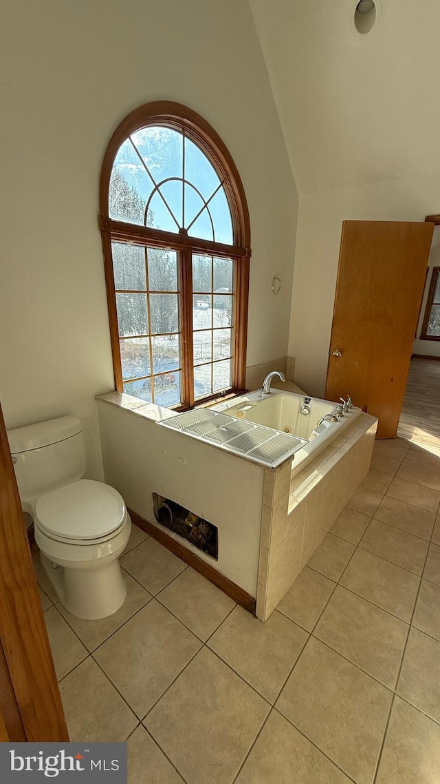 bathroom featuring toilet, vaulted ceiling, tile patterned flooring, and tiled tub