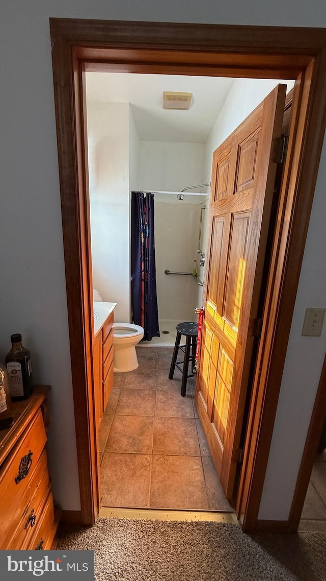 bathroom featuring toilet, vanity, tile patterned floors, and a shower with curtain