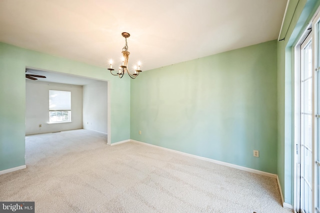 carpeted spare room featuring an inviting chandelier