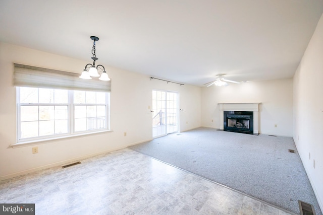 unfurnished living room with light colored carpet and ceiling fan with notable chandelier