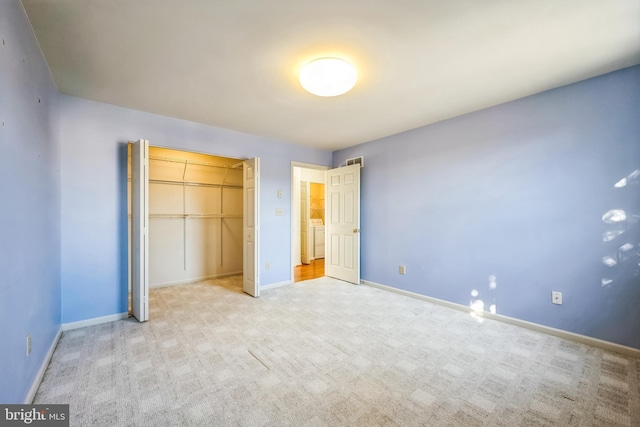 unfurnished bedroom featuring a closet, washer / clothes dryer, and light carpet