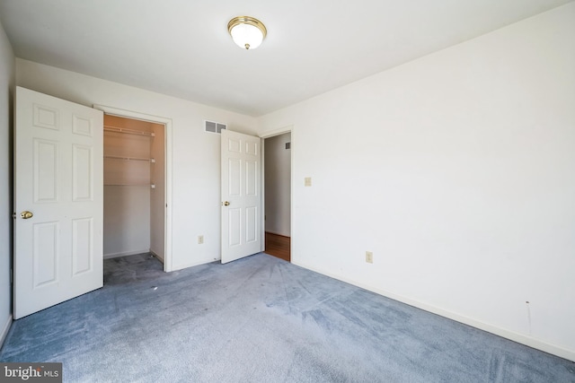 unfurnished bedroom featuring a walk in closet, carpet, and a closet