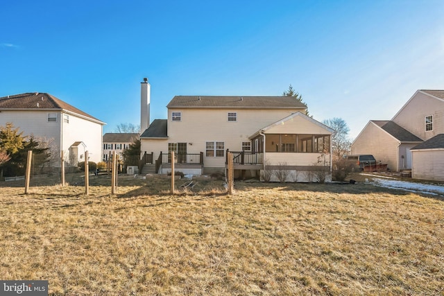 back of house with a sunroom and a lawn