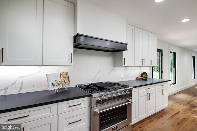 kitchen with white cabinets, light hardwood / wood-style floors, high end stove, and custom range hood