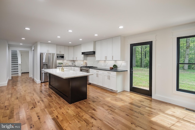 kitchen featuring a center island, white cabinetry, stainless steel appliances, and light hardwood / wood-style flooring