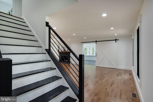 stairway with a barn door and hardwood / wood-style flooring