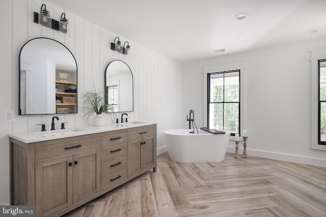 bathroom featuring a bathtub, vanity, and parquet flooring