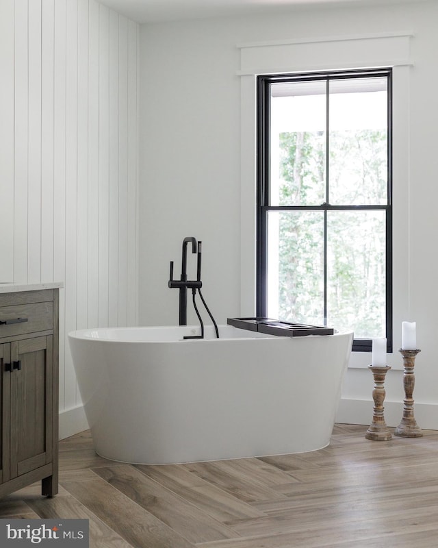 bathroom with hardwood / wood-style flooring, a bathtub, and a healthy amount of sunlight