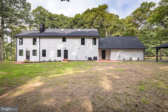 rear view of property featuring a yard, cooling unit, and a patio area