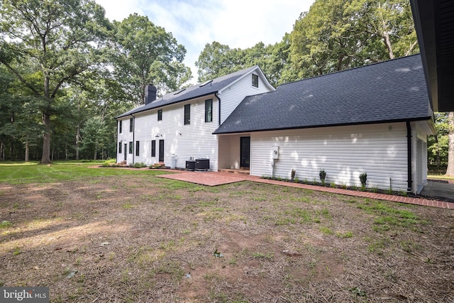 rear view of house featuring a yard, cooling unit, and a patio area