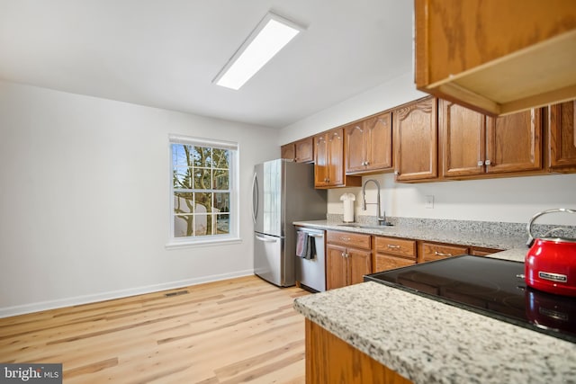 kitchen featuring light stone counters, sink, light hardwood / wood-style flooring, and stainless steel appliances