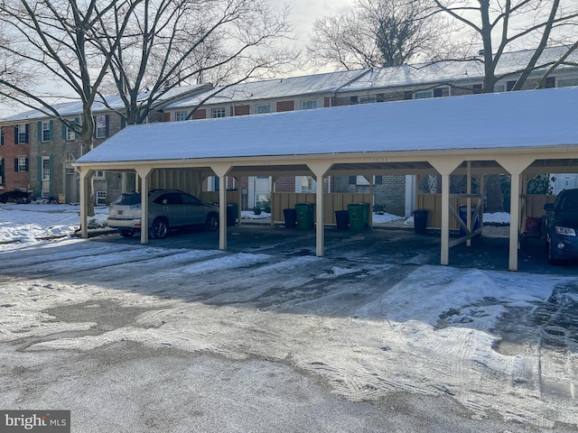 snow covered parking area featuring a carport