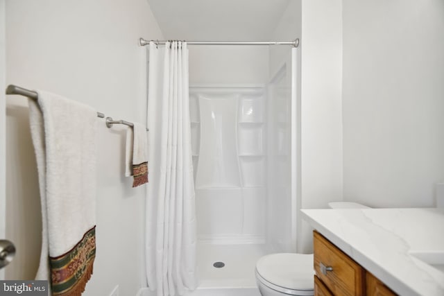 bathroom featuring toilet, vanity, and walk in shower