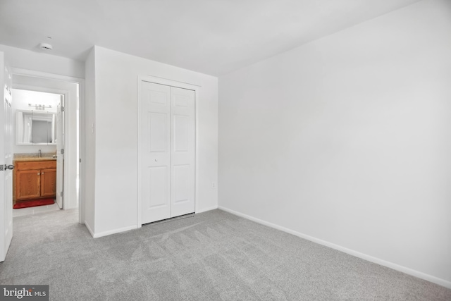 unfurnished bedroom with light carpet, sink, and a closet