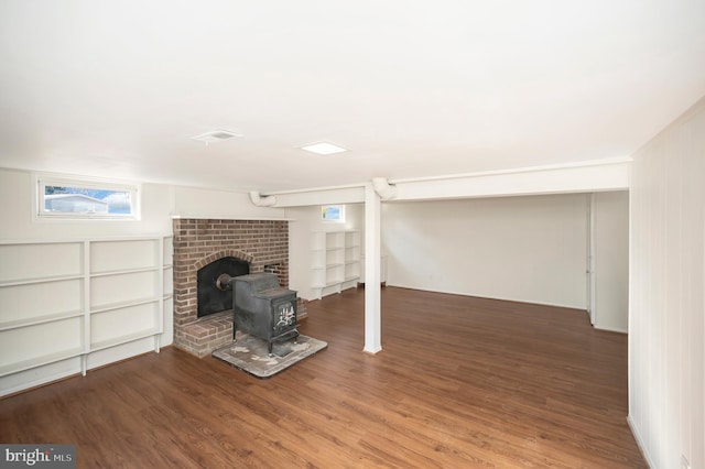 basement featuring a wood stove and dark hardwood / wood-style flooring