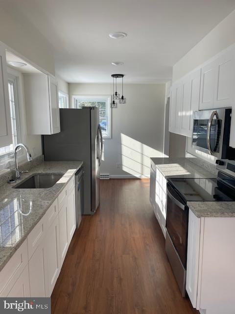 kitchen featuring white cabinetry, stainless steel appliances, decorative light fixtures, and sink