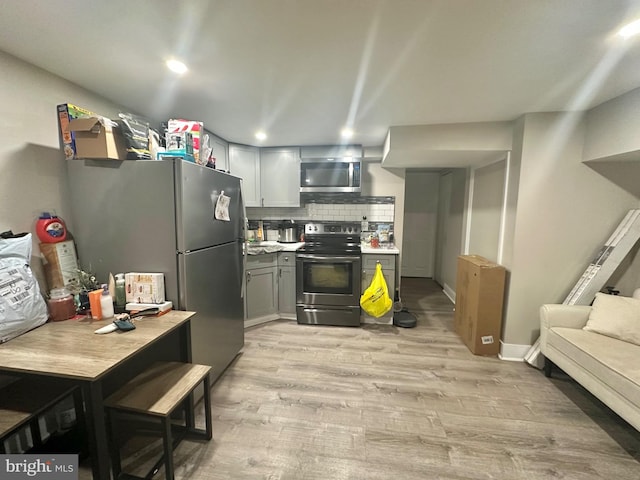 kitchen with gray cabinetry, decorative backsplash, light hardwood / wood-style floors, and stainless steel appliances