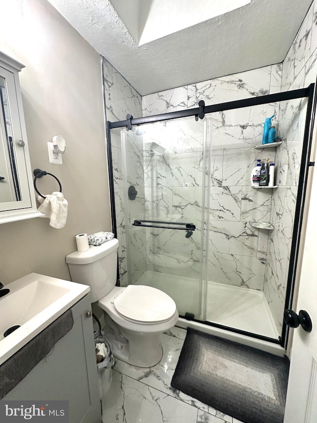 bathroom with vanity, toilet, a shower with shower door, and a textured ceiling