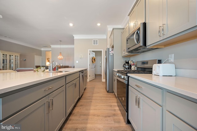 kitchen featuring stainless steel appliances, gray cabinetry, pendant lighting, crown molding, and sink