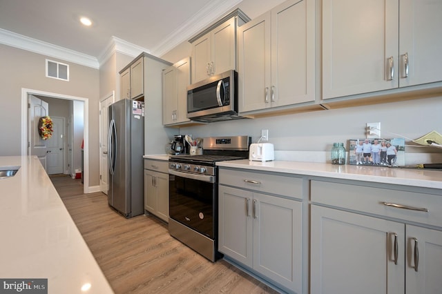 kitchen featuring ornamental molding, gray cabinetry, stainless steel appliances, and light hardwood / wood-style flooring