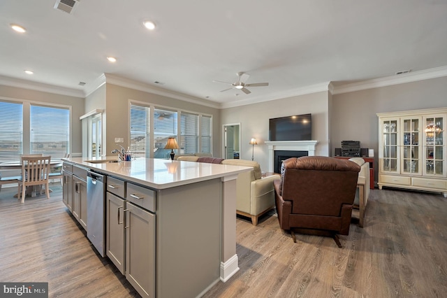 kitchen featuring ceiling fan, stainless steel dishwasher, sink, an island with sink, and gray cabinetry