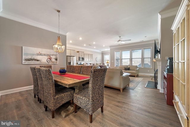 dining room with dark hardwood / wood-style floors, ceiling fan with notable chandelier, and crown molding