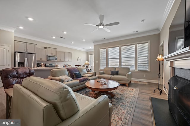 living room with ceiling fan, hardwood / wood-style floors, ornamental molding, and a fireplace