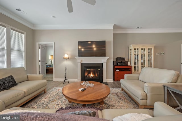 living room featuring hardwood / wood-style flooring, crown molding, and ceiling fan