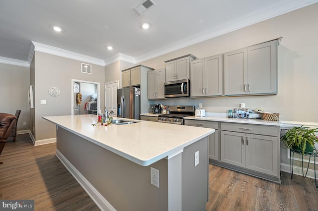 kitchen featuring dark hardwood / wood-style floors, appliances with stainless steel finishes, a center island with sink, and gray cabinetry