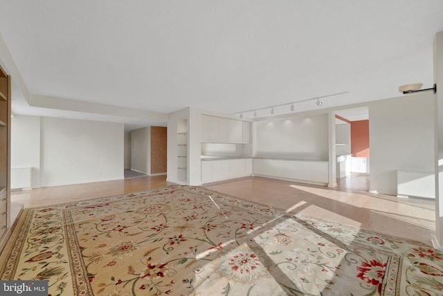 unfurnished living room with track lighting and built in shelves