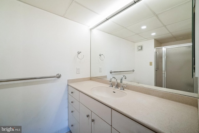 bathroom featuring vanity, a shower with shower door, and a drop ceiling