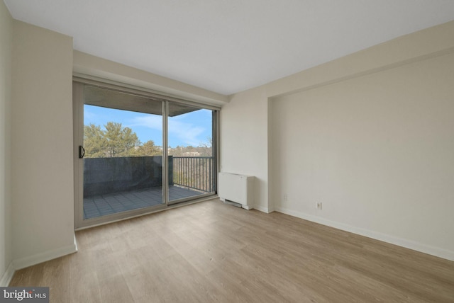 spare room featuring radiator heating unit and light hardwood / wood-style floors