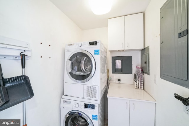 washroom featuring electric panel, cabinets, and stacked washing maching and dryer