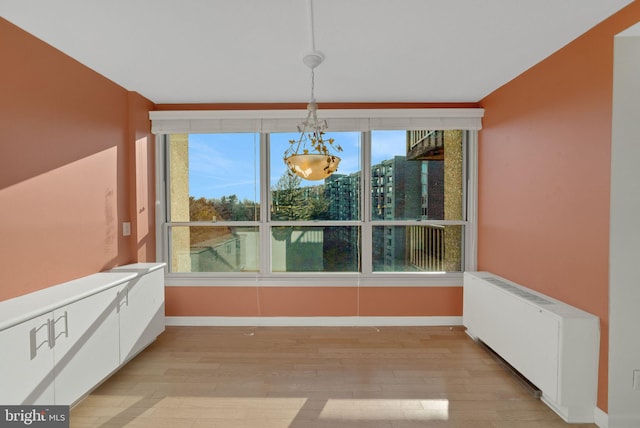 unfurnished dining area featuring radiator and light hardwood / wood-style floors