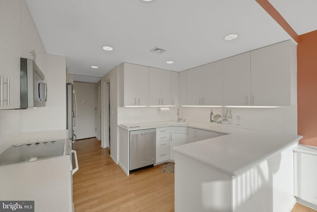 kitchen featuring stainless steel appliances, white cabinets, backsplash, and light hardwood / wood-style flooring