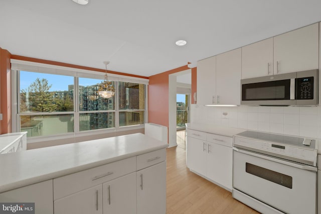 kitchen featuring decorative light fixtures, tasteful backsplash, white cabinets, light hardwood / wood-style floors, and electric stove