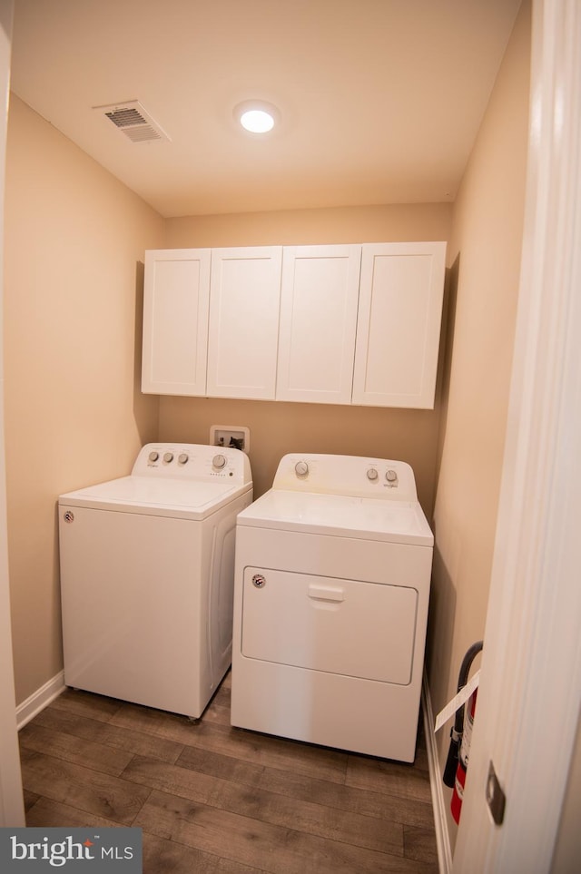 washroom featuring dark wood-type flooring, cabinets, and independent washer and dryer