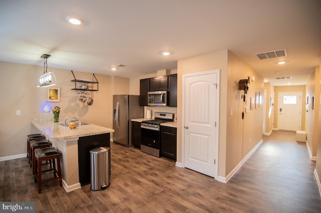 kitchen with a kitchen breakfast bar, hanging light fixtures, light stone counters, kitchen peninsula, and stainless steel appliances