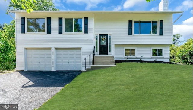 bi-level home with a front yard, a garage, driveway, and a chimney