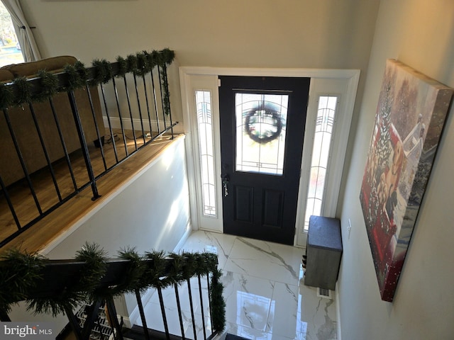 foyer featuring plenty of natural light, marble finish floor, and stairway