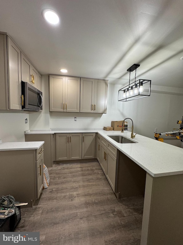 kitchen with dark hardwood / wood-style floors, decorative light fixtures, sink, gray cabinetry, and kitchen peninsula