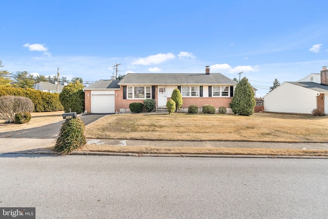 view of front of house featuring a garage, a front lawn, aphalt driveway, and brick siding