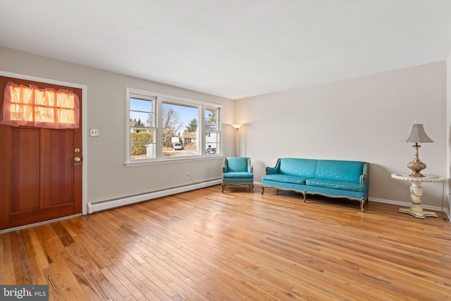 unfurnished room with a baseboard heating unit, light wood-type flooring, and baseboards