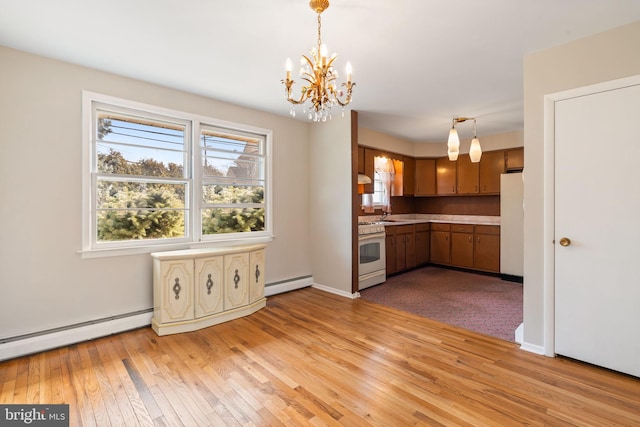 kitchen with a baseboard heating unit, white appliances, light countertops, light wood finished floors, and decorative light fixtures